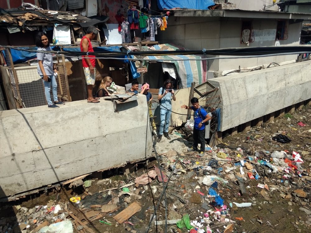 Students examining riverside dwellings in Philippines