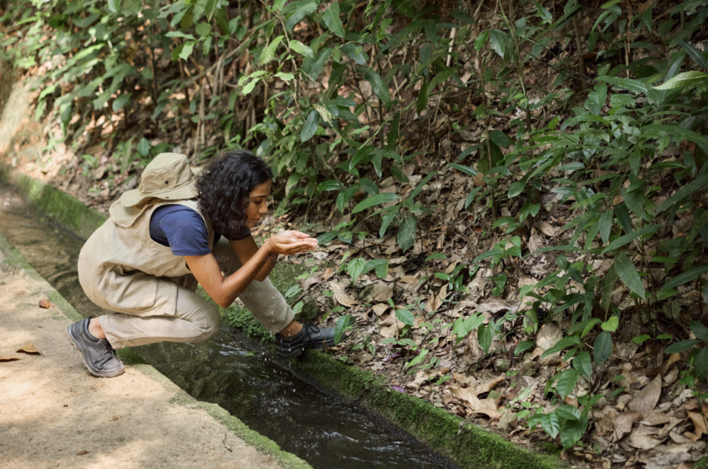 Woman catching water in her hands from a stream
