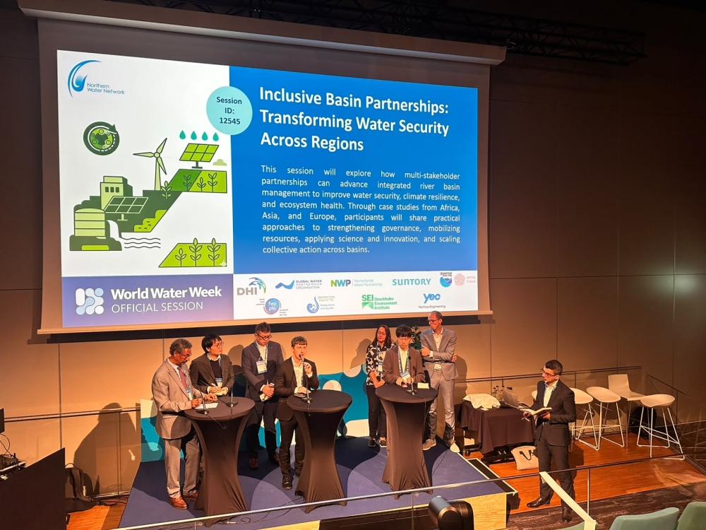 Eight conference speakers on a stage and one moderator involved in panel discussion