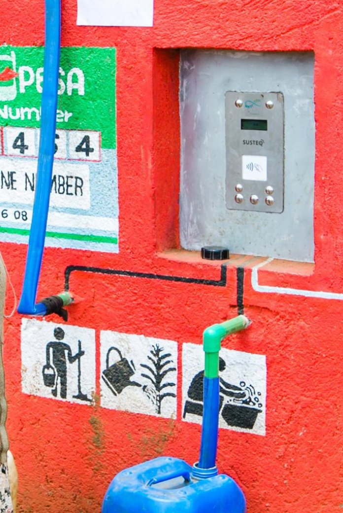 Photo of a woman taking water from a water point using the Susteq prepaid system.