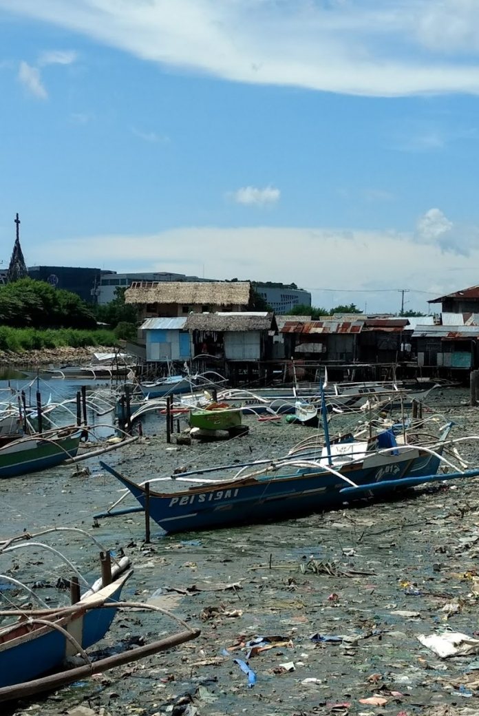 Riverside in Philippines, with boats and pollution