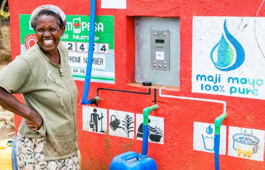 Photo of a woman taking water from a water point using the Susteq prepaid system.