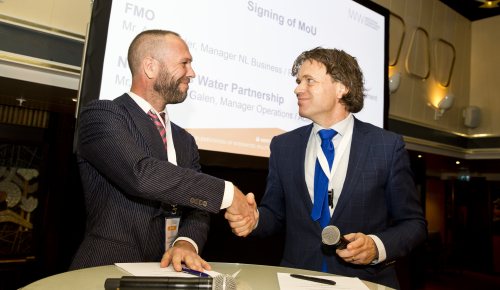 NWP acting director Ewout van Galen and Aart Mulder of FMO Development Bank shake hands on the renewal of the MoU at the AIWW Summit 2018