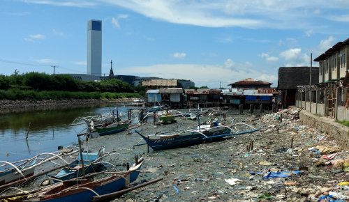 Riverside in Philippines, with boats and pollution